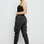 An angled back view of a smiling woman in black utility joggers womens.