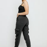 An angled back view of a smiling woman in black utility joggers womens.