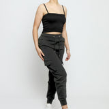 Full length shot of a woman wearing black utility joggers womens and white trainers.