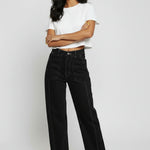 Model standing with arms crossed styling black utility pants with a white t-shirt.