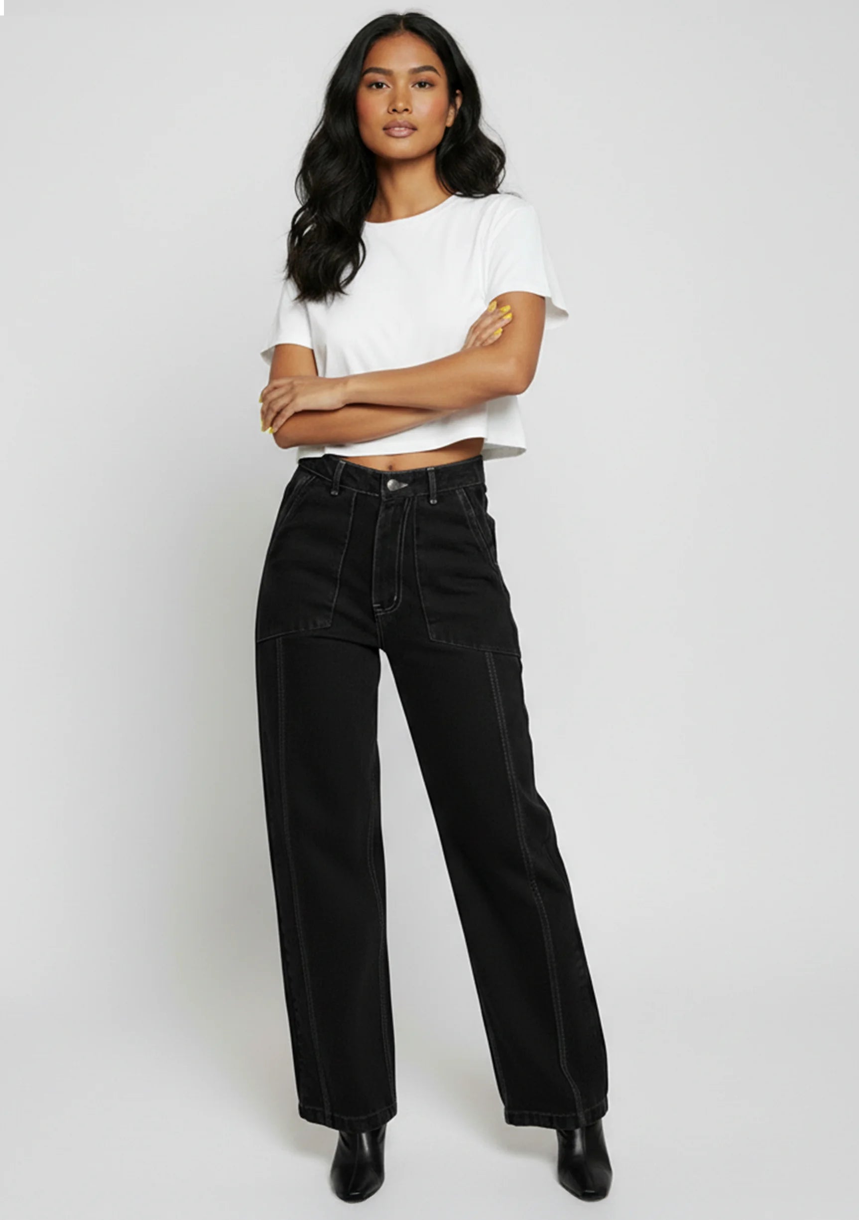 Model standing with arms crossed styling black utility pants with a white t-shirt.