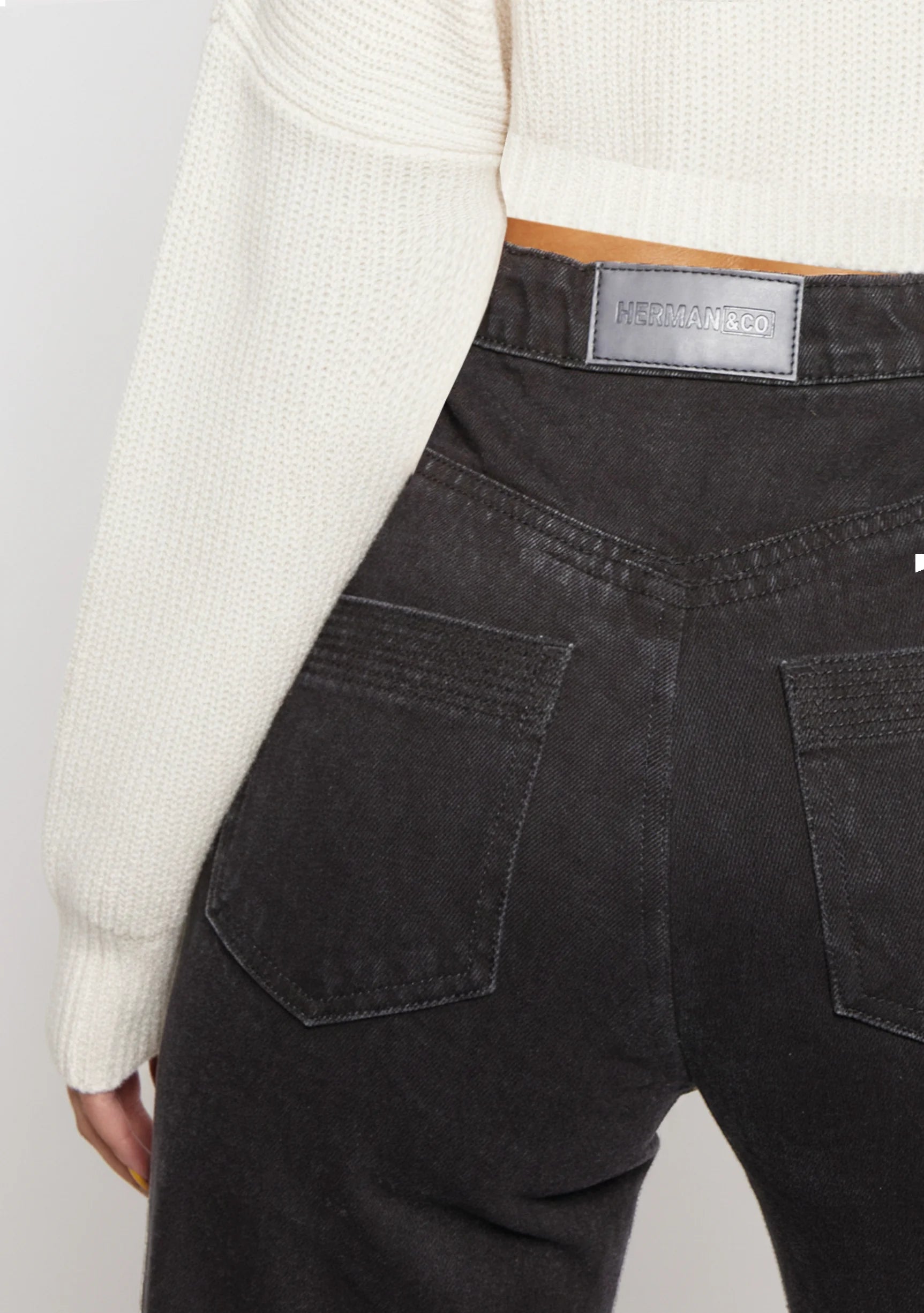 Close up of back pockets and brand patch on Black Wash Curved Seam Straight Leg Jeans