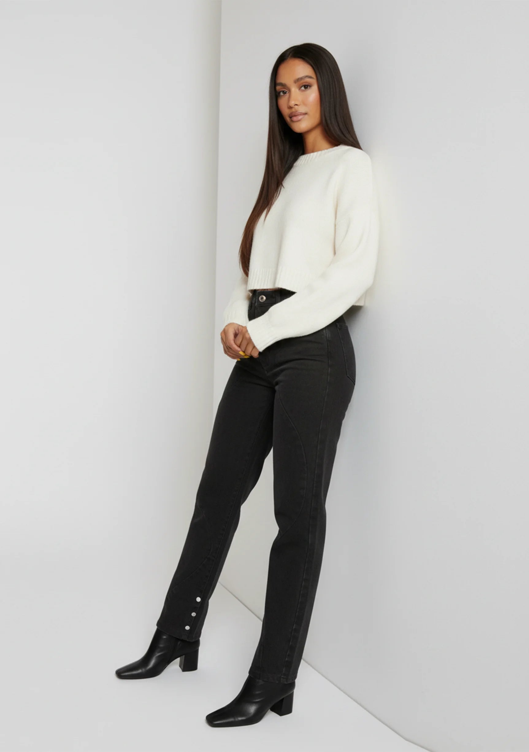 Model leaning against the wall wearing Black Wash Curved Seam Straight Leg Jeans