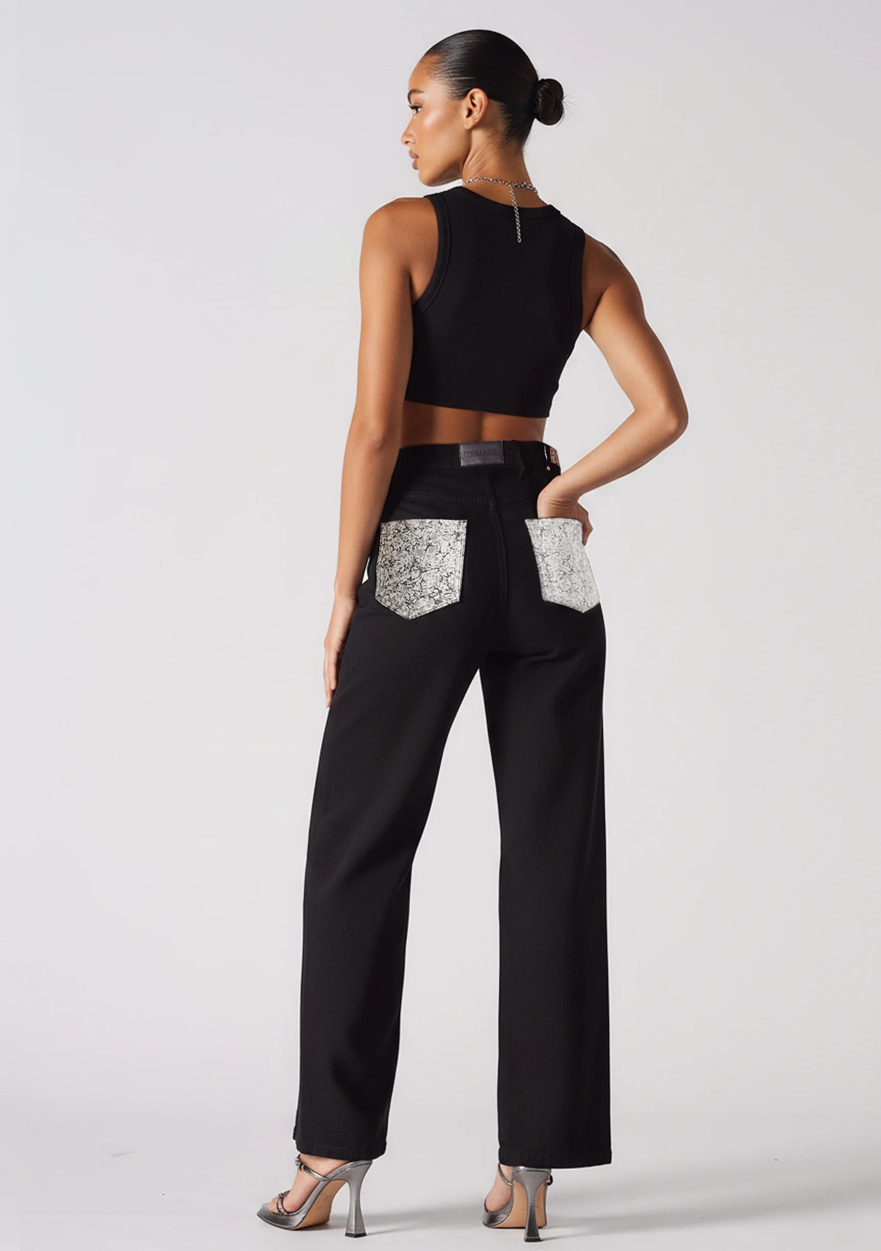 Angled back view showing silver embellished pocket details on black wide leg jeans