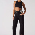 Side walking view showing the drape and slit hem of black embellished jeans