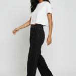 Model walking in high-waist black wide-leg jeans showing the side drape and movement.