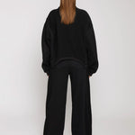 Rear view of black wide leg joggers paired with a black oversized sweatshirt