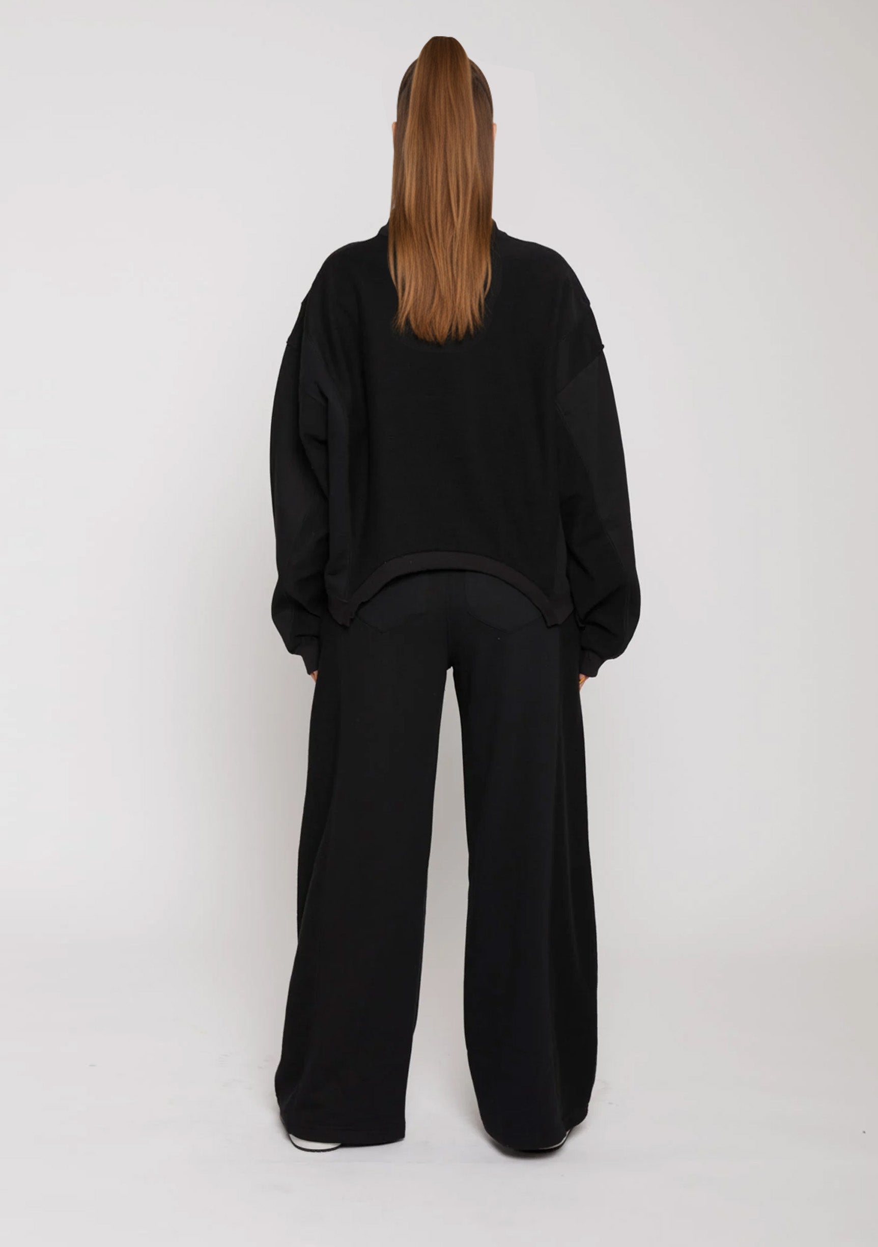 Rear view of black wide leg joggers paired with a black oversized sweatshirt