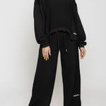 A woman posing in comfortable black wide leg joggers and a long sleeve top