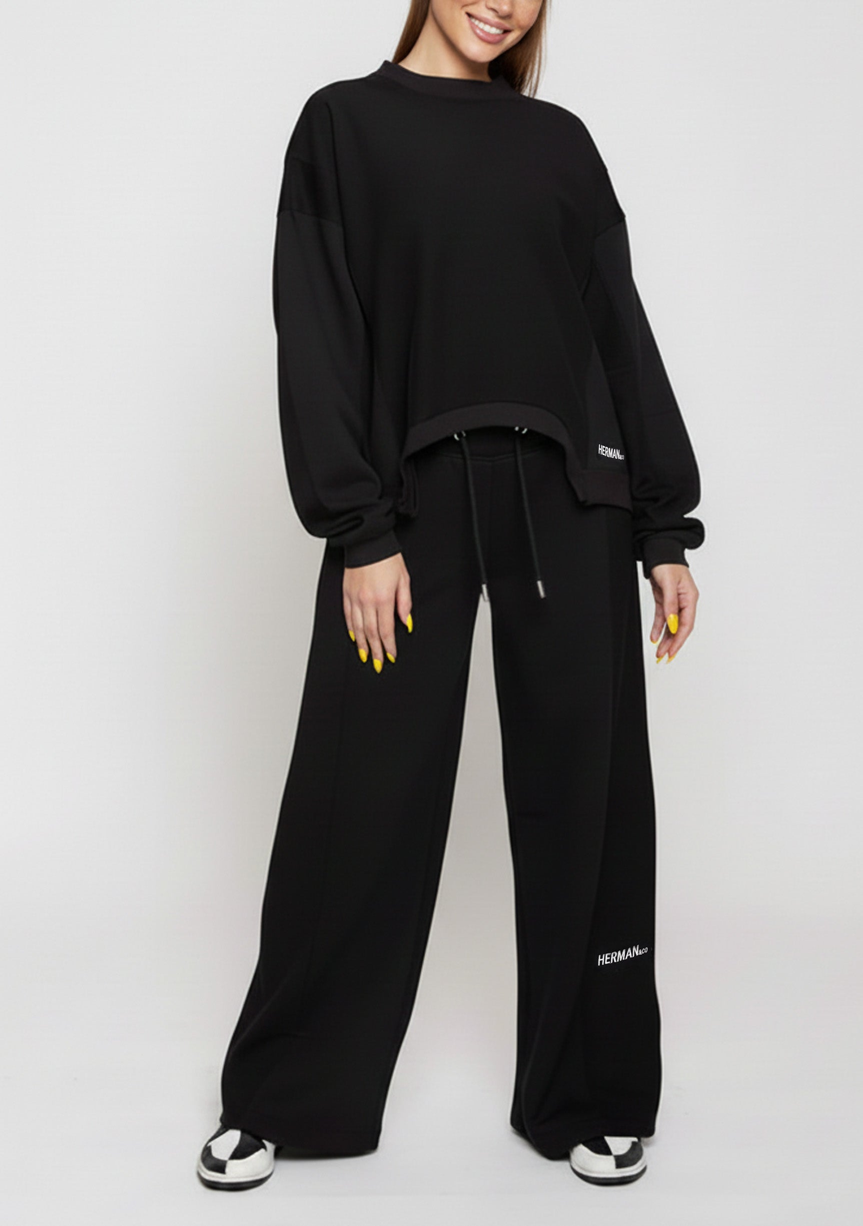 A woman posing in comfortable black wide leg joggers and a long sleeve top