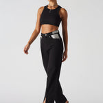 Front walking pose highlighting the front slit hem on black wide leg jeans