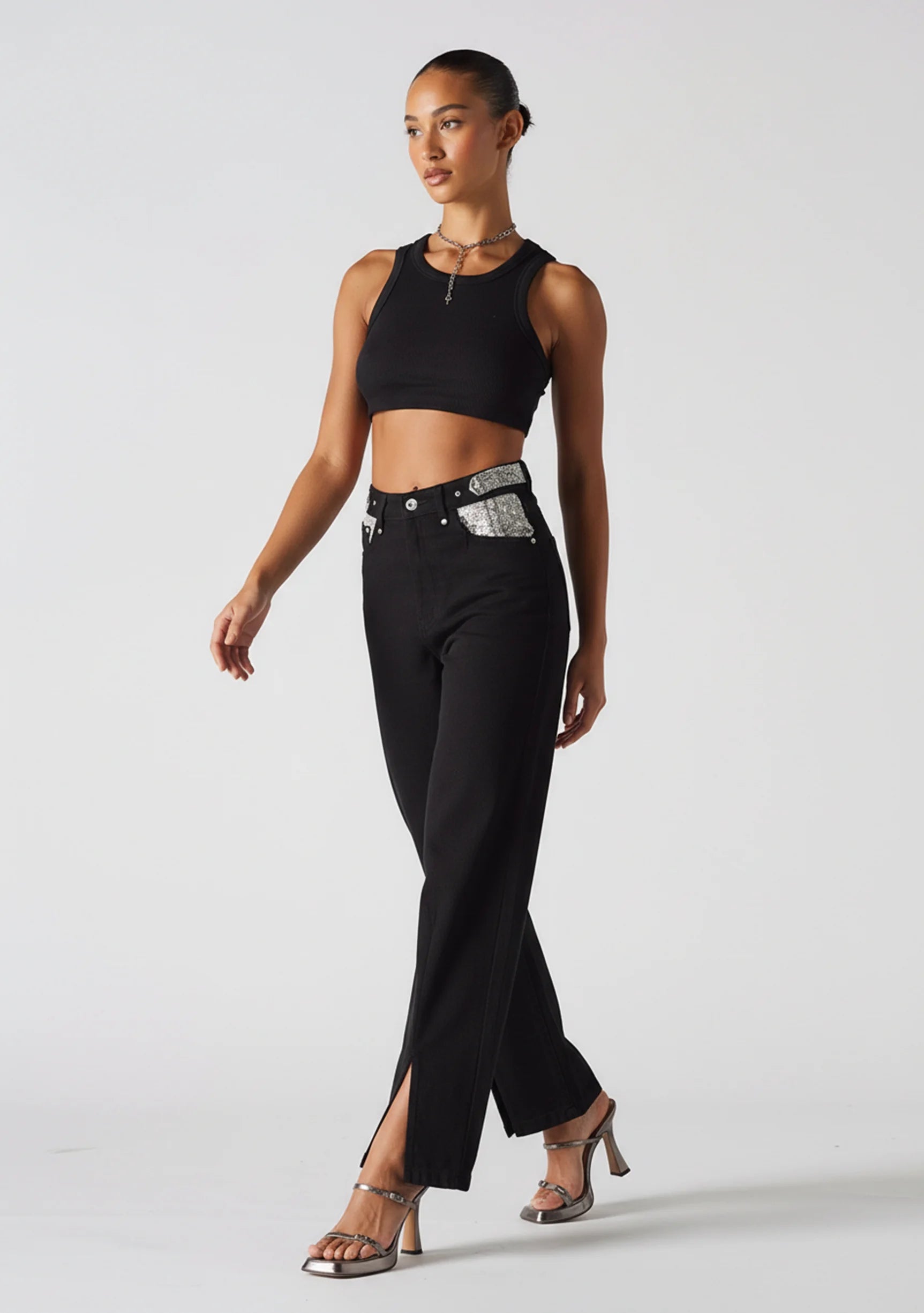 Front walking pose highlighting the front slit hem on black wide leg jeans