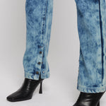 Close-up of silver poppers on bleach wash jeans hem