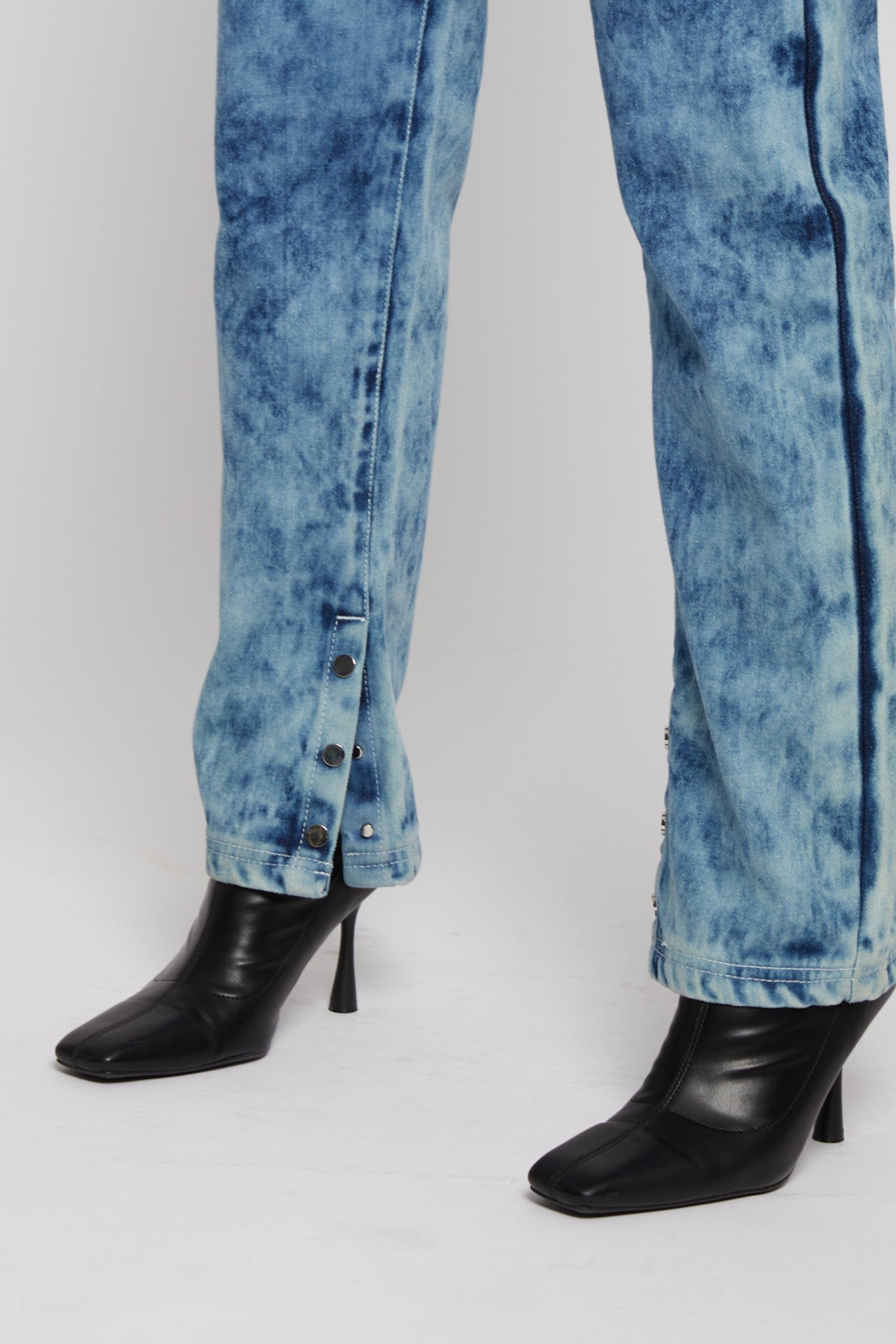 Close-up of silver poppers on bleach wash jeans hem