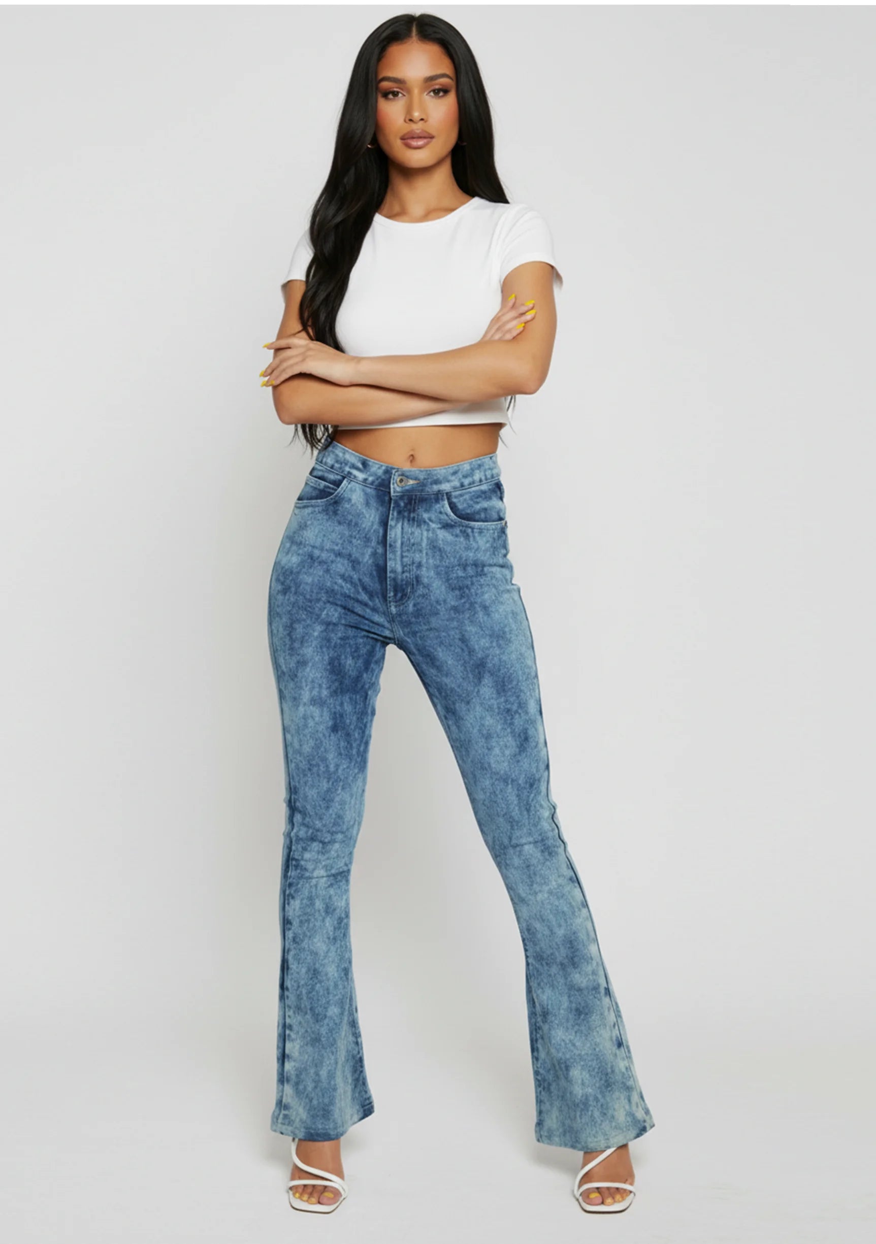 Model with arms crossed wearing fitted blue acid wash bootcut jeans