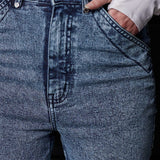Close-up of the unique front pocket design on the blue acid wash jeans