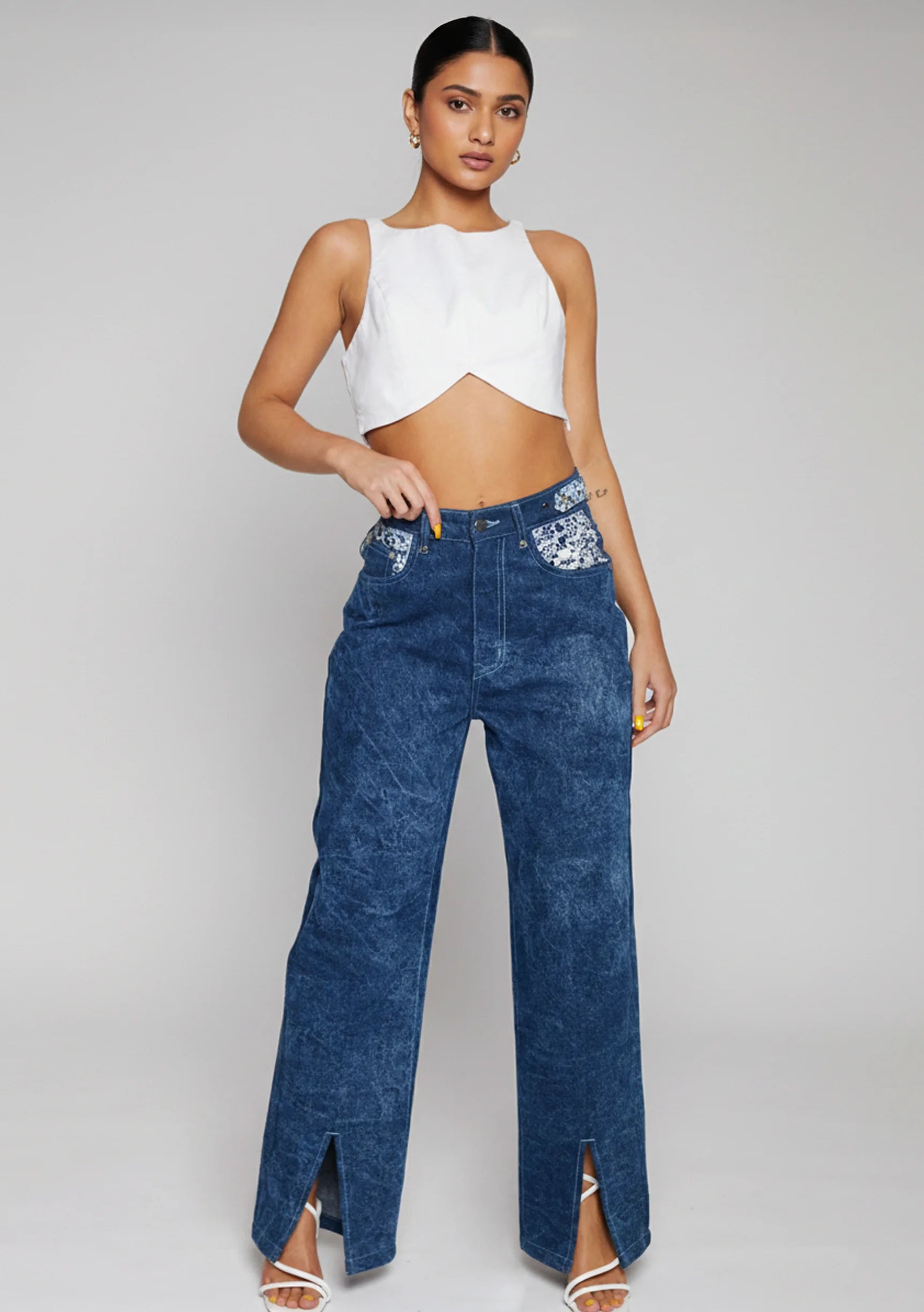 Front view of women's blue acid wash wide leg jeans with embellished pockets and slit hems