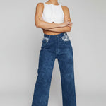 Studio shot of model wearing blue wide leg jeans with embellished pockets