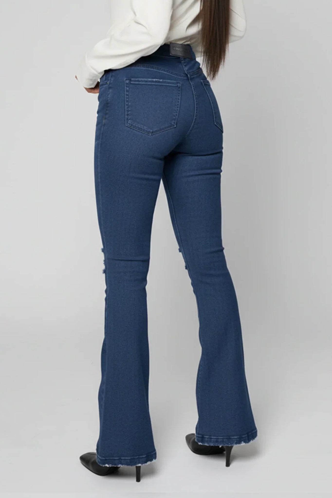 Person wearing blue flared jeans on a plain background