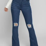 Blue flared jeans with distressed details worn by a person on a white background