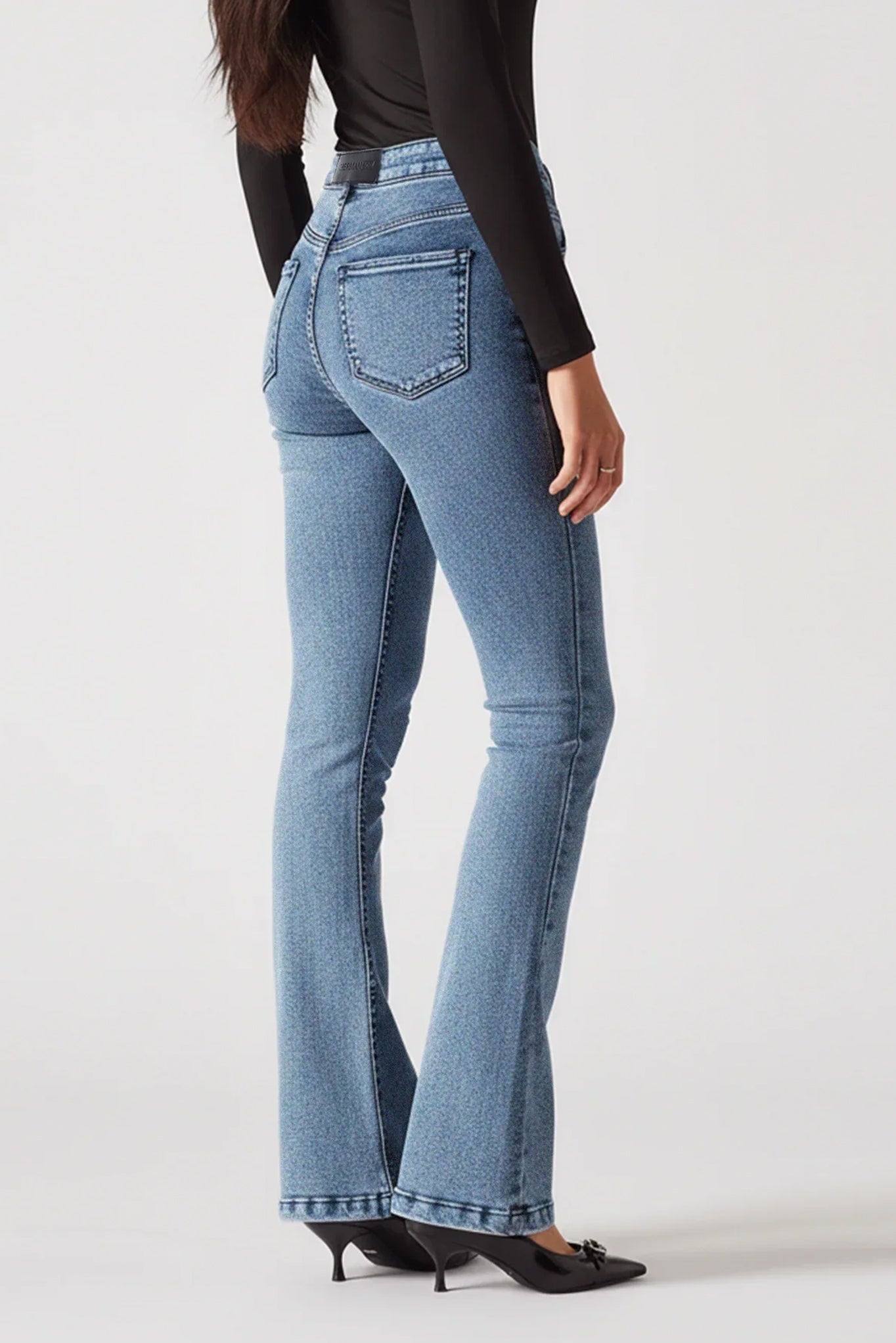 Person wearing blue flared jeans on a white background