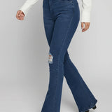 Person wearing blue flared jeans on a plain background