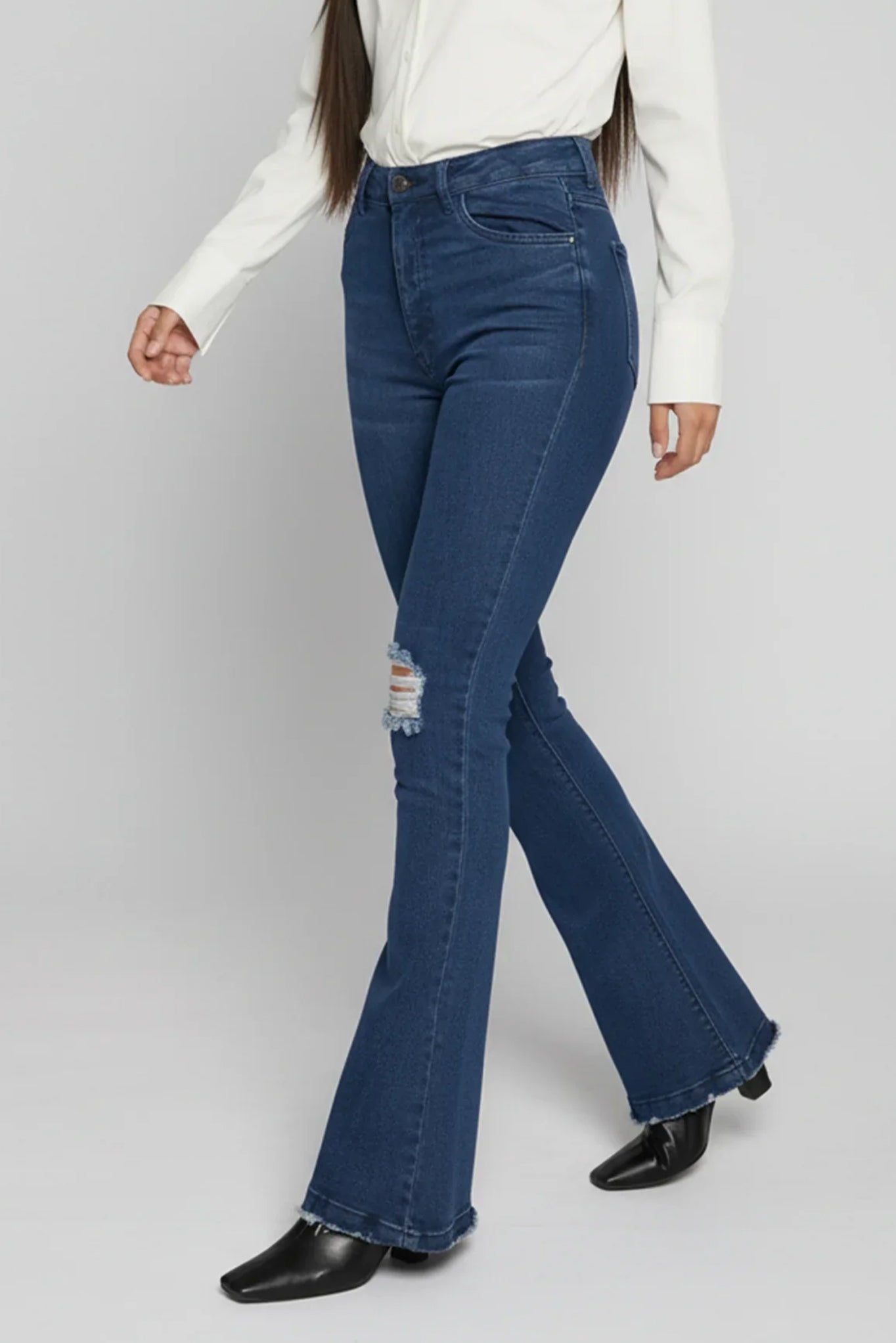 Person wearing blue flared jeans on a plain background
