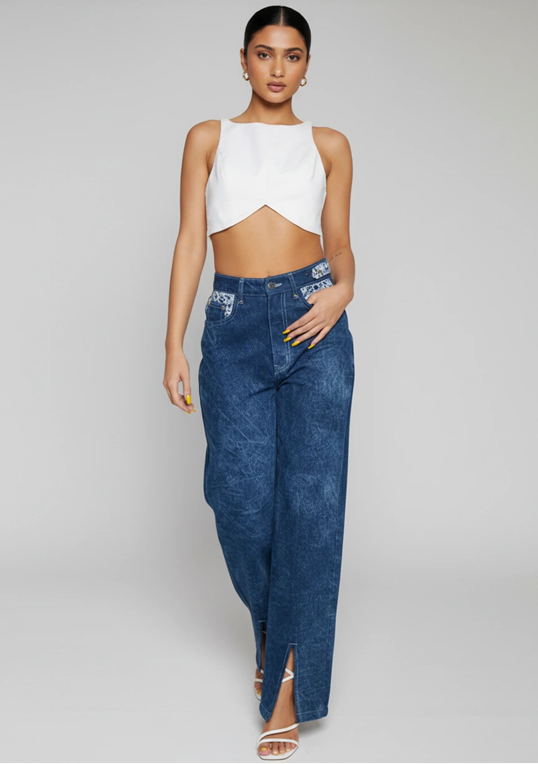 Close up of the button closure and belt loops on blue acid wash high-waisted jeans