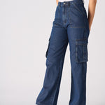 An angled front shot of a woman wearing blue wide leg cargo jeans for women with a beige top.