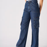 An angled front shot of a woman wearing blue wide leg cargo jeans for women with a beige top.