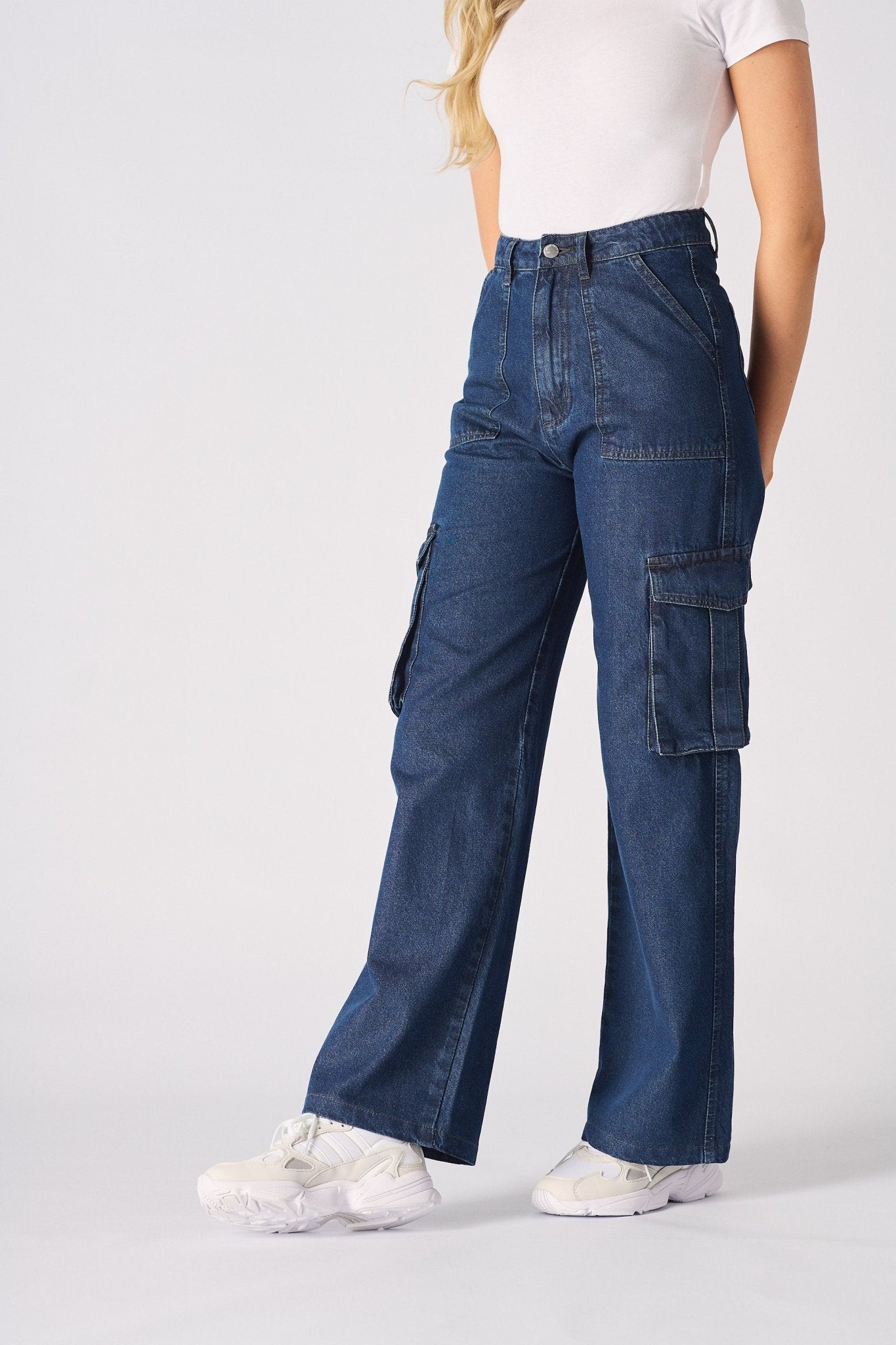 An angled front shot of a woman wearing blue wide leg cargo jeans for women with a beige top.