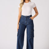 A model posing in blue high waisted wide leg cargo denim jeans women with her hands on the waistband.