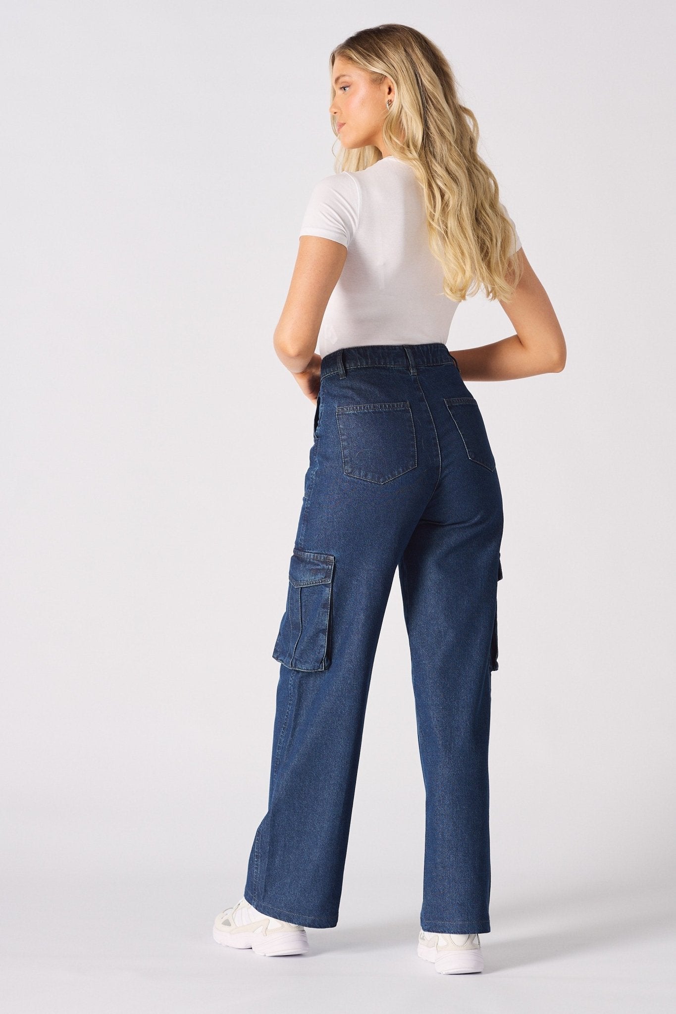 Rear view of a model in blue high waisted wide leg cargo denim jeans women showing the flattering fit.