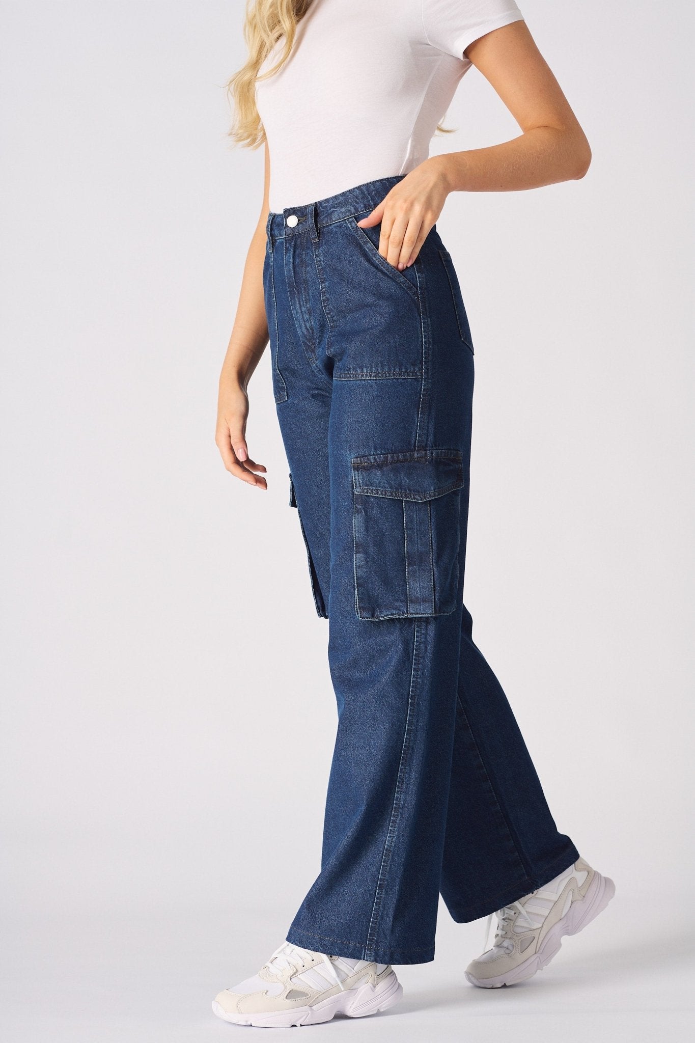 Side profile view of a model walking in blue high waisted wide leg cargo denim jeans women.