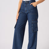 A woman standing in blue high waisted wide leg cargo denim jeans women highlighting the relaxed leg silhouette.