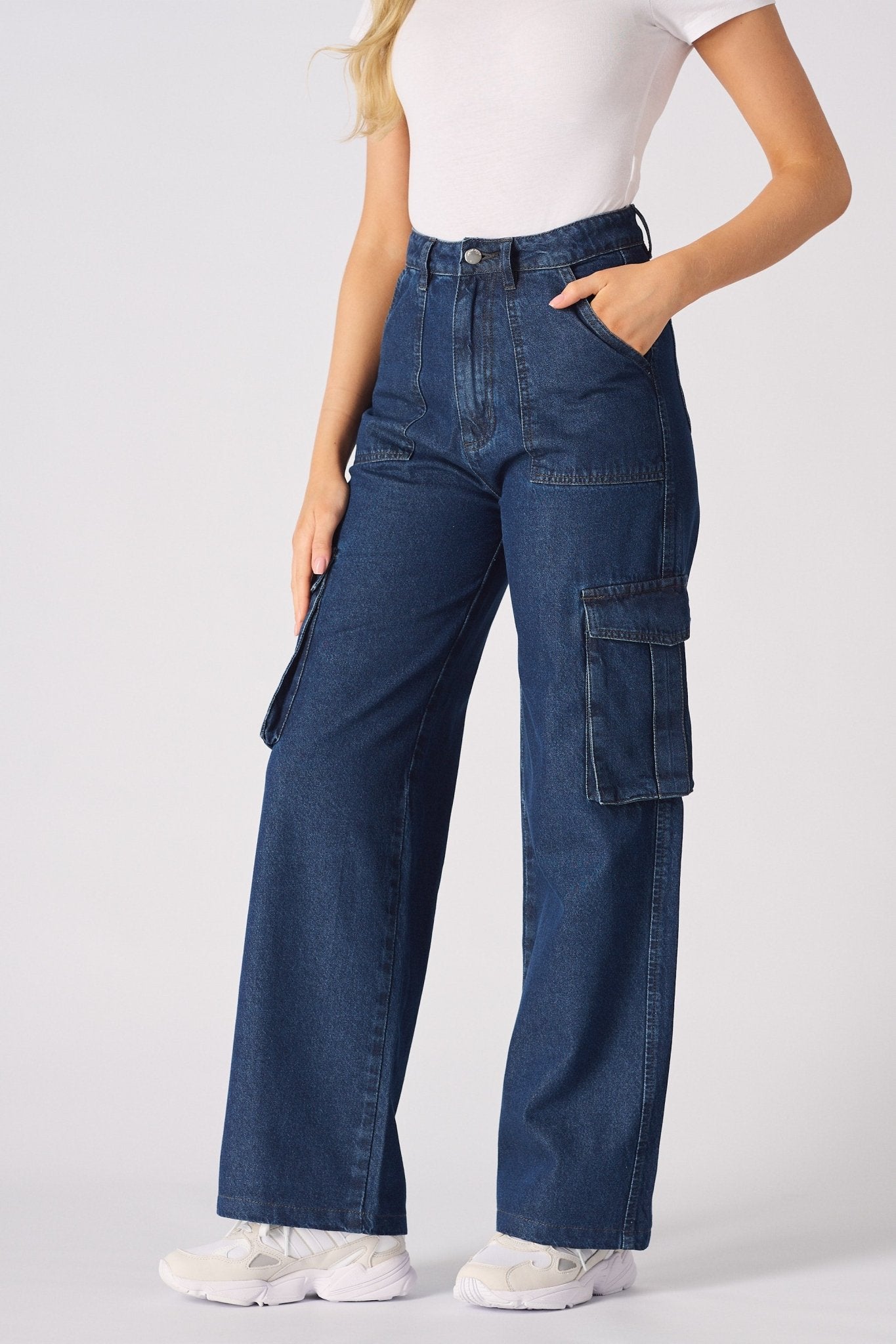 A woman standing in blue high waisted wide leg cargo denim jeans women highlighting the relaxed leg silhouette.