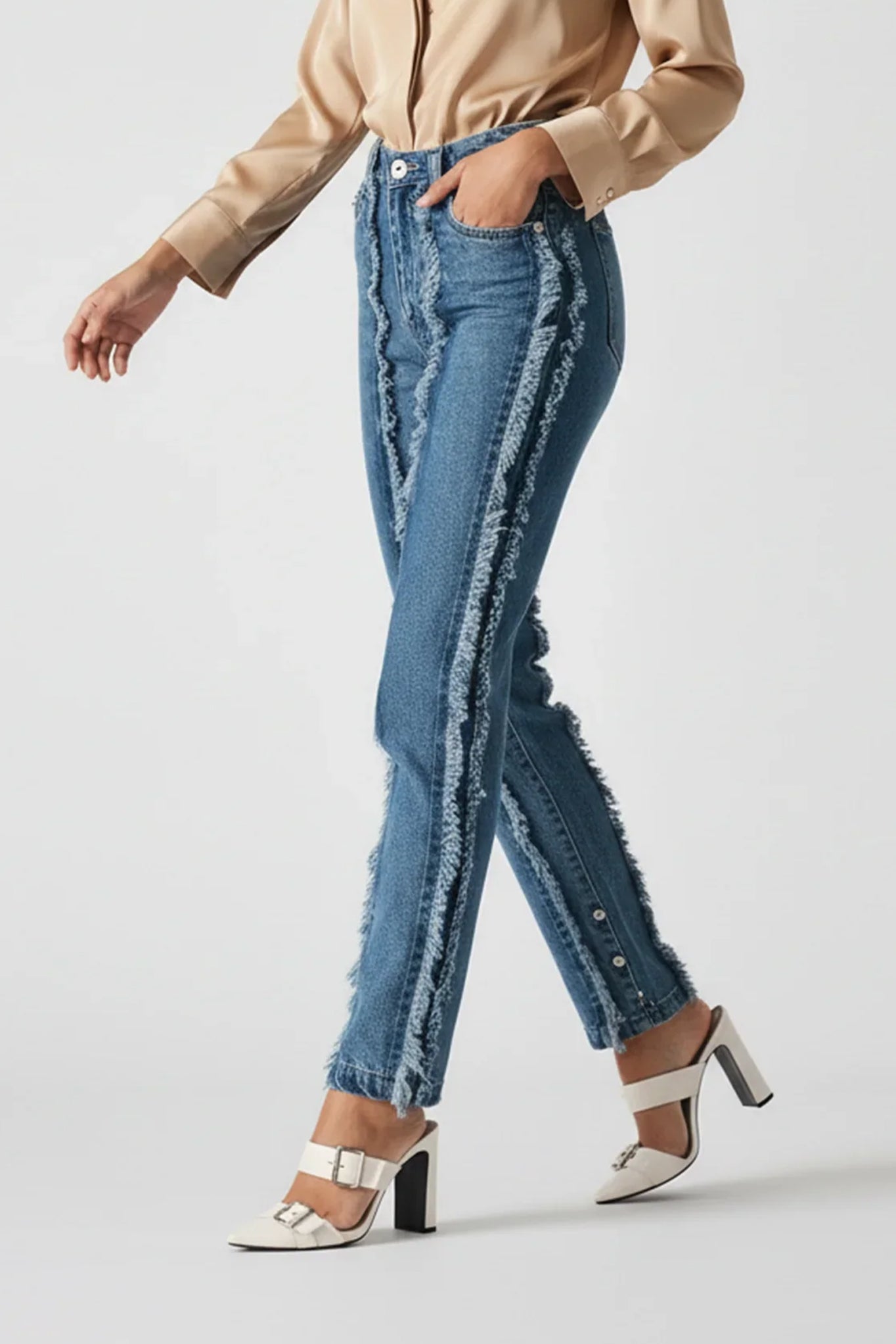 Person wearing blue jeans and a beige shirt on a white background