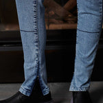 Close-up of blue jeans and black shoes on a dark background