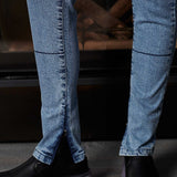 Close-up of blue jeans and black shoes on a dark background
