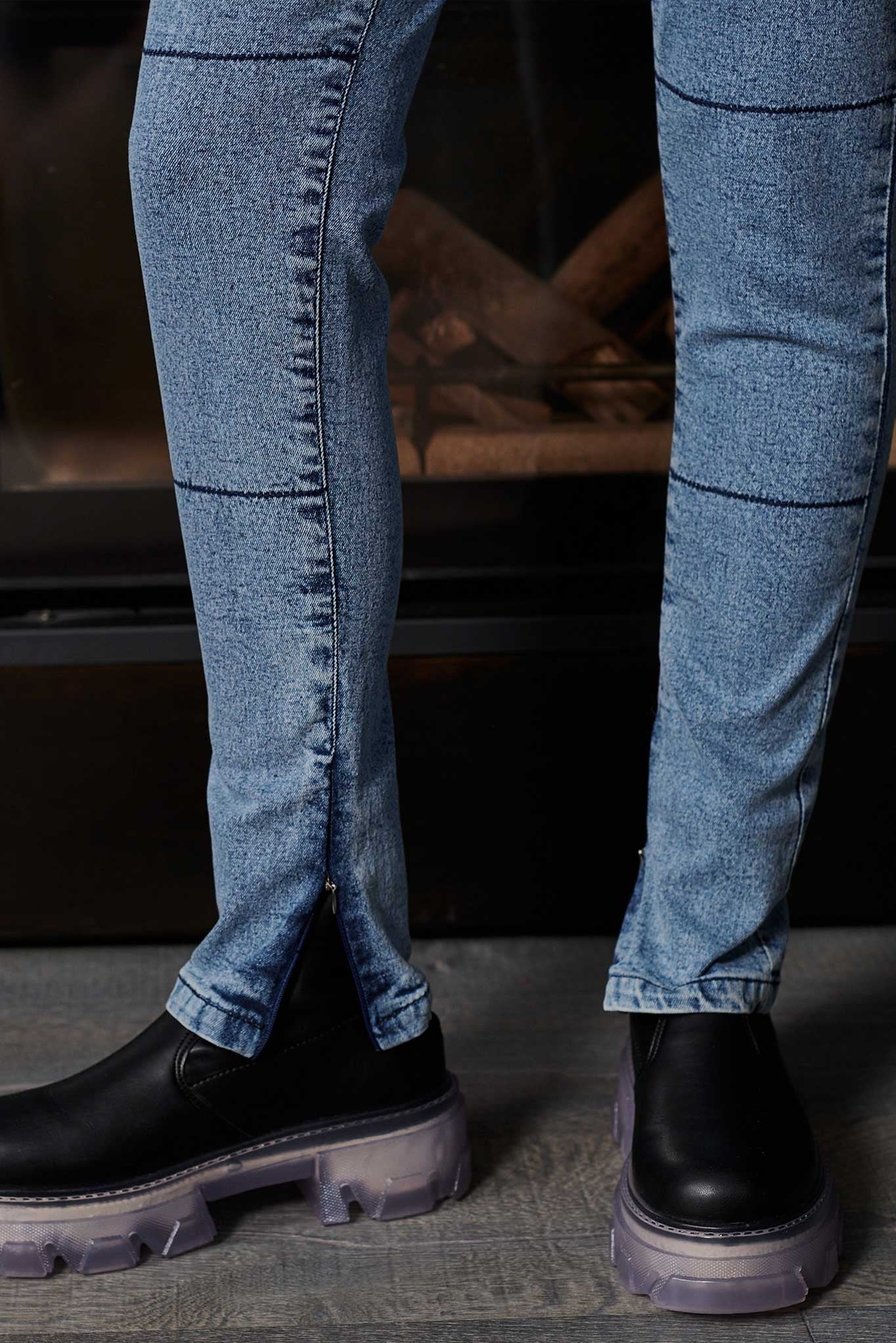 Close-up of blue jeans and black shoes on a dark background