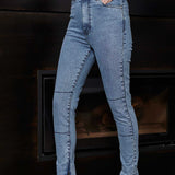 Person wearing blue jeans and black shoes in front of a fireplace.