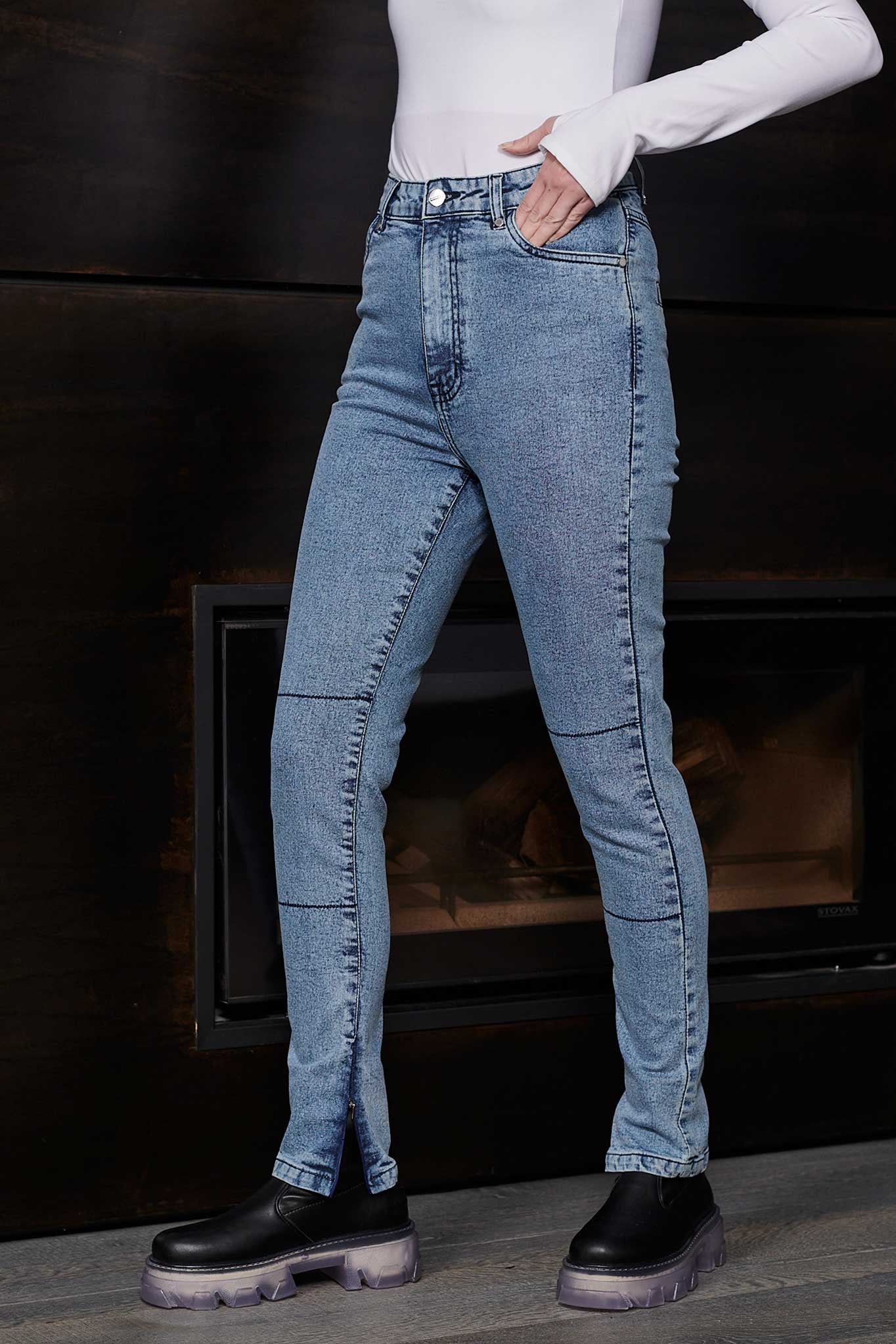 Person wearing blue jeans and black shoes in front of a fireplace.