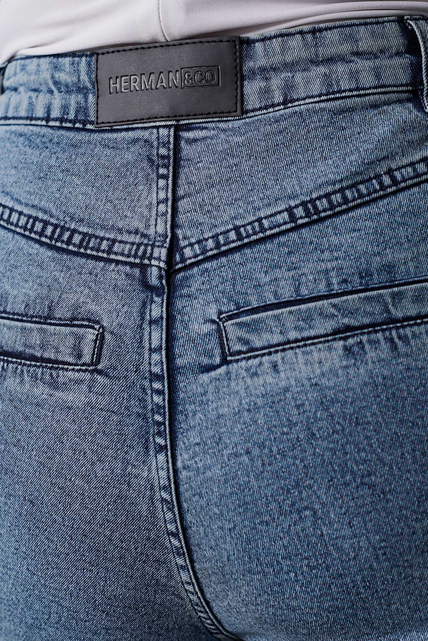 Close-up of blue jeans with a visible brand label on the waistband.