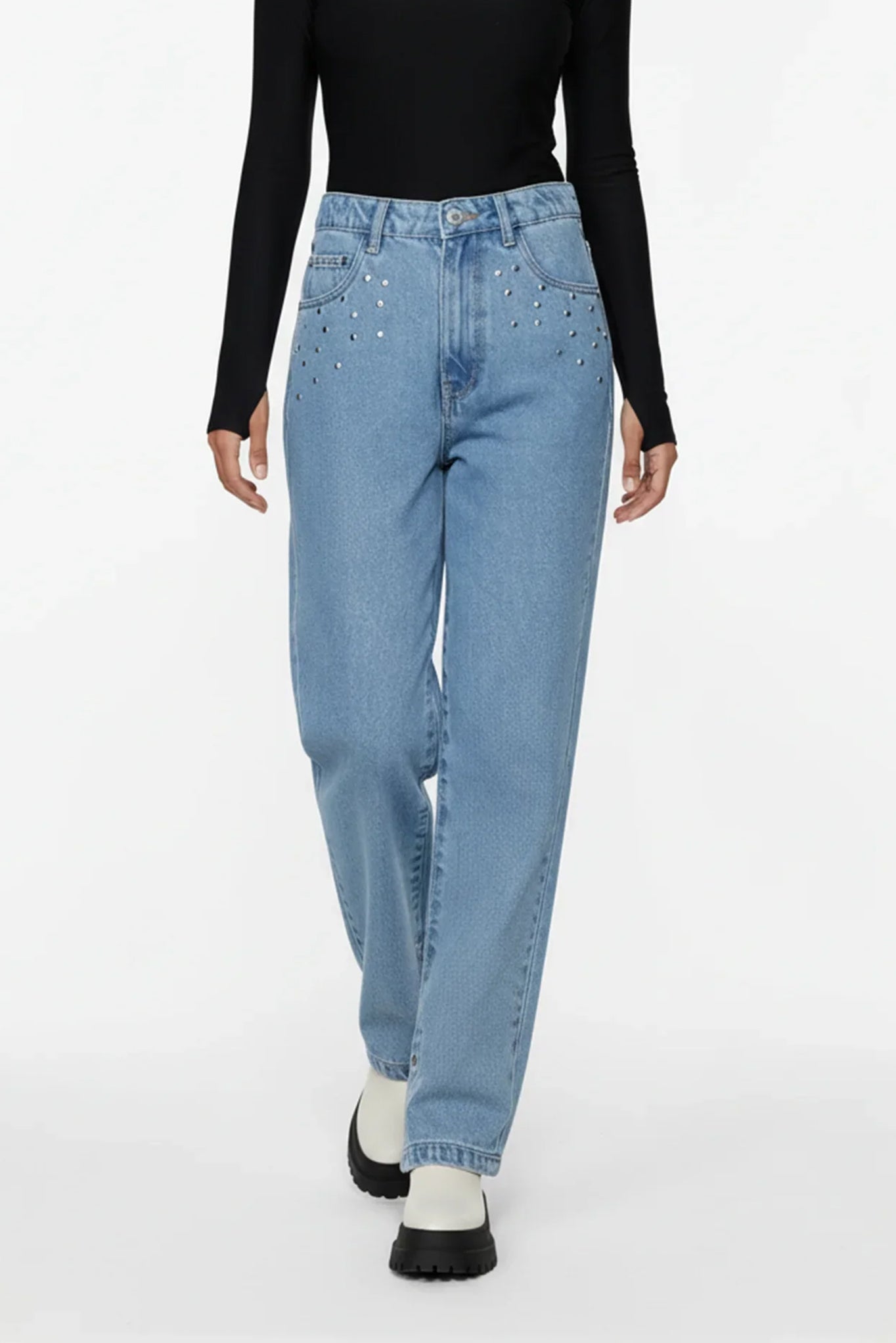 Person wearing blue jeans with decorative elements on a white background