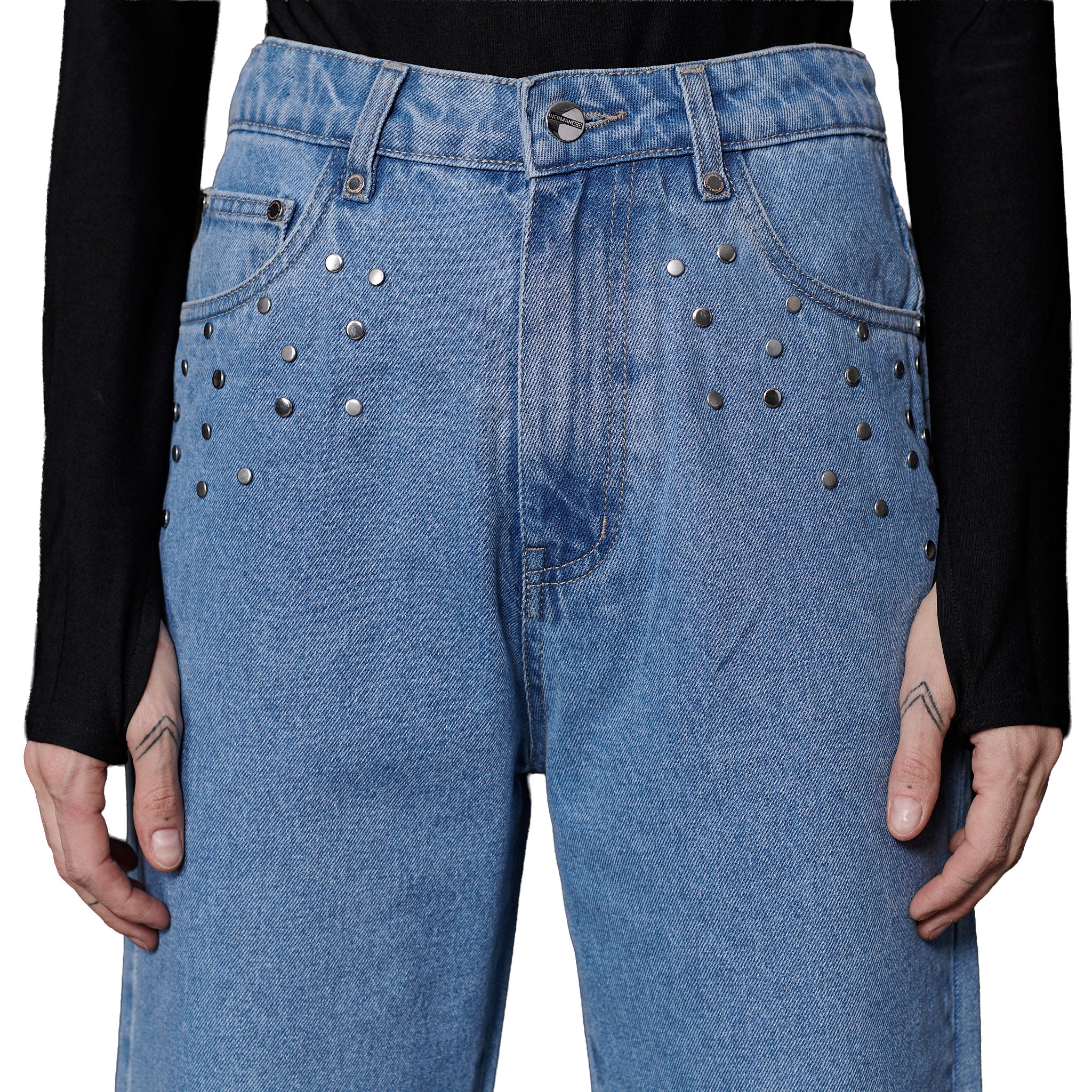 Blue jeans with decorative studs worn by a person against a black background