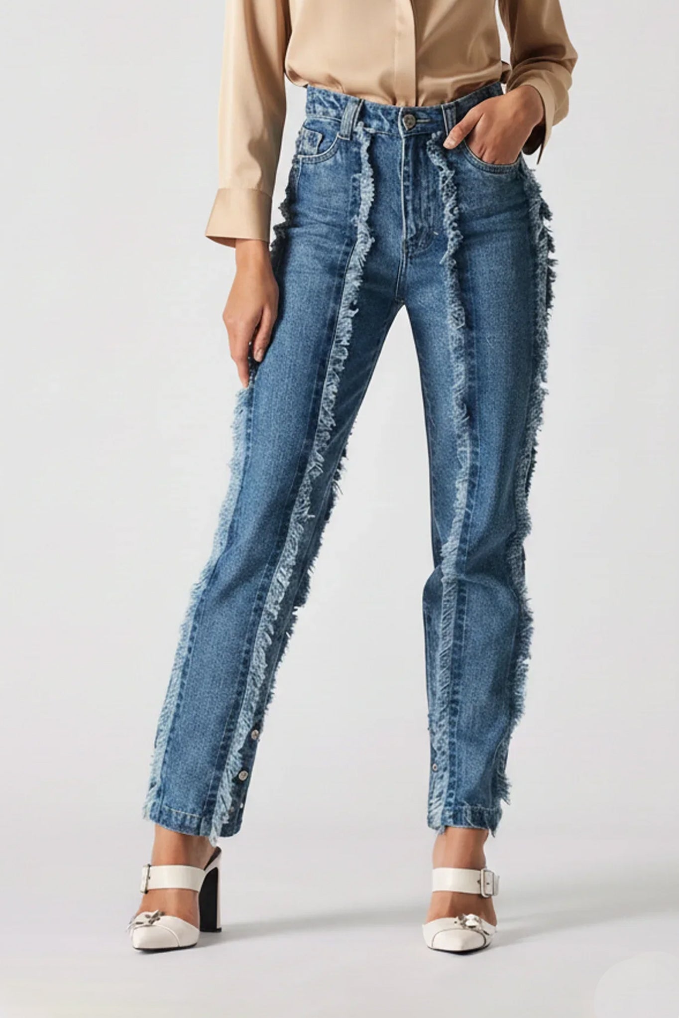 Person wearing blue jeans with frayed edges on a white background