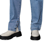 Close-up of rolled-up blue jeans with white shoes and black boots on a white background
