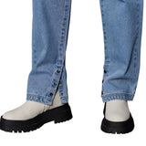 Close-up of rolled-up blue jeans with white shoes and black boots on a white background