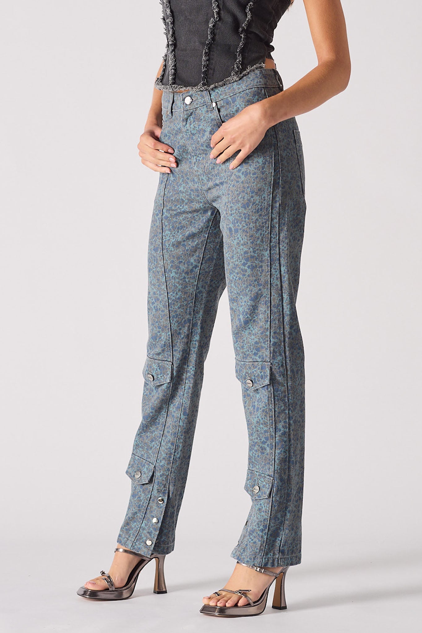 Person wearing blue pants with button details on a plain background