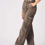 An angled shot of the model wearing brown cargo jeans for women focusing on the functional side pockets.